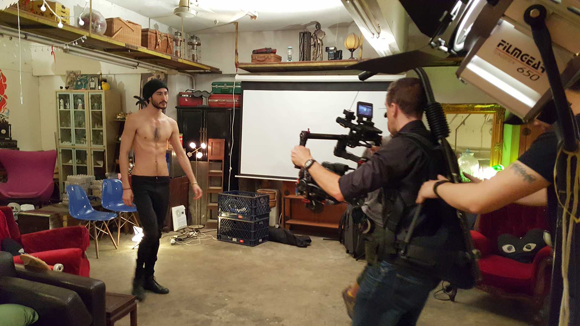 Behind the scenes shot of a cameraman using a Ronin to film a male model.