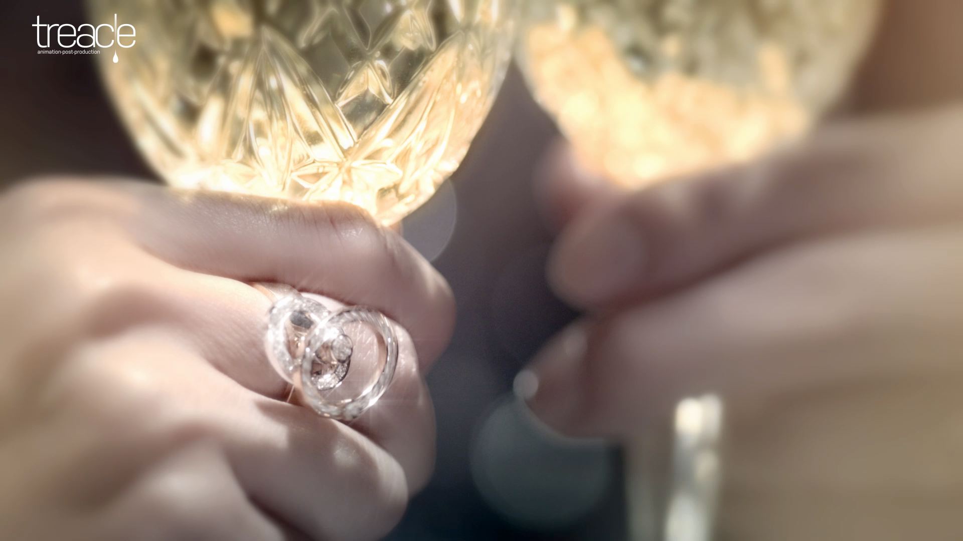 Close-up of a diamond ring on a woman's hand holding a champagne glass.