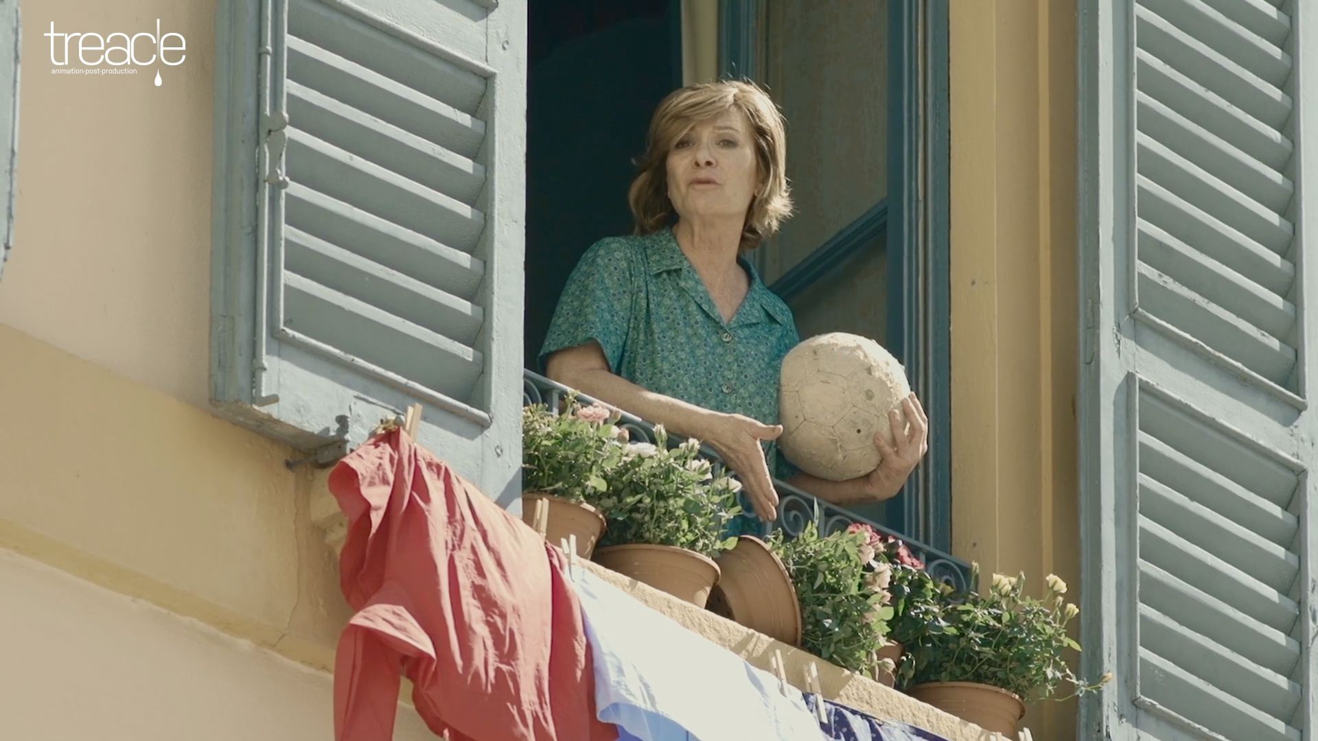 An Italian woman holding a football standing at her window